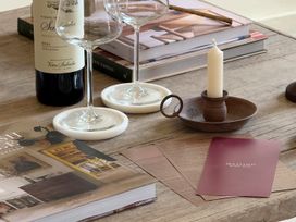 A living room table with wine glasses, a wine bottle, candle, and books at Church Alley House Stow-On-The-Wold