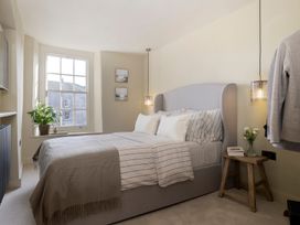 A bedroom with a bed, bedside table, and plant at Church Alley House Stow-On-The-Wold