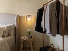 A bedroom with suits on a rack and a bedside table at Church Alley House Stow-On-The-Wold