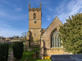 A church with a clock tower and trees at Church Alley House Stow-On-The-Wold