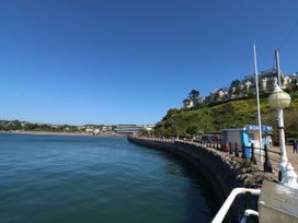 A view of a waterfront with a pier and surrounding buildings at Hares Cottage in Torquay