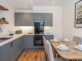 A kitchen with cabinets and dining table at Hares Cottage in Torquay
