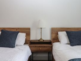 A bedroom with two beds and a nightstand at Hares Cottage in Torquay