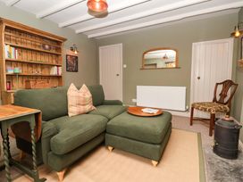 A snug with a sofa and bookshelf at The Cook’s Cottage in Malton