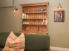 A snug with a wooden shelf and books at The Cook’s Cottage in Malton