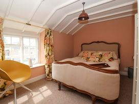 A bedroom with a bed and a chair at The Cook’s Cottage in Malton