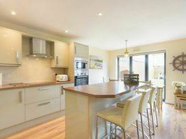 A kitchen with cabinets and a dining area at Beach Walk in Chathill