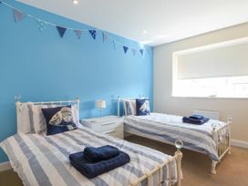 A bedroom with two single beds and a bedside table at Beach Walk in Chathill