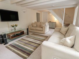 A living room with a television and seating at Woodbine Cottage in Weymouth