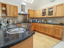 A kitchen with wooden cabinets and appliances at Woodbine Cottage in Weymouth