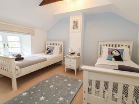 A bedroom with two beds and a nightstand at Woodbine Cottage in Weymouth