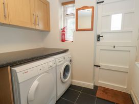 A laundry room with a washing machine and tumble dryer at Woodbine Cottage in Weymouth