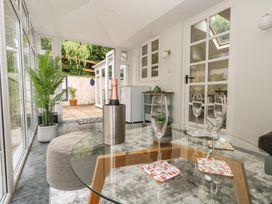 A conservatory with a table and wine glasses at Woodbine Cottage in Weymouth