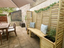 A garden with a table, chairs, and a wooden bench at Woodbine Cottage in Weymouth