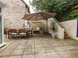 A garden with a table and chairs under an umbrella at Woodbine Cottage in Weymouth