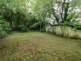 A garden with trees and a wall at Woodbine Cottage in Weymouth