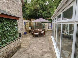 An outdoor patio with a table and chairs under an umbrella at Woodbine Cottage in Weymouth