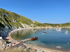 A beach with boats and people at Woodbine Cottage in Osmington
