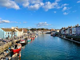 A view of boats along a river with buildings at Woodbine Cottage in Osmington