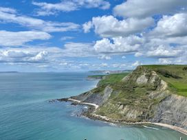 A view of cliffs and ocean under a cloudy sky at Woodbine Cottage in Osmington