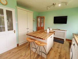 A kitchen with cabinets and a dining area at Campden in Rennington near Embleton
