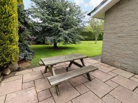 A garden with a wooden picnic table on a paved patio at Campden in Rennington near Embleton