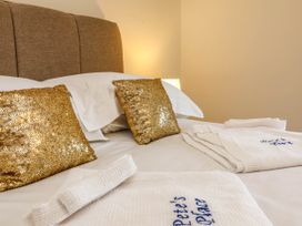 A bed with gold throw pillows and towels at Pete's Place in Taunton