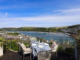 An outdoor dining area with a table and chairs overlooking the water at Dart Views in Dartmouth
