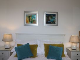 A bedroom with a bed, pillows, lamps, and wall art at Dart Views in Dartmouth