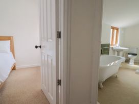 A bedroom with a bed and a door leading to a bathroom at Saybrook Cottage Charmouth