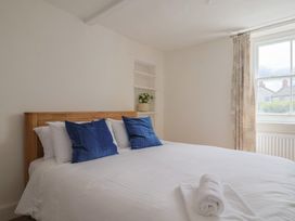 A bedroom with a bed and curtains at Saybrook Cottage in Charmouth