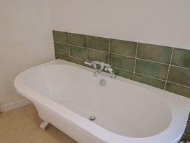 A bathtub with green wall tiles at Saybrook Cottage in Charmouth