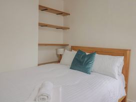 A bedroom with a bed and shelves at Saybrook Cottage in Charmouth