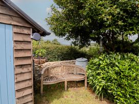 A garden with a wooden bench and a storage container at Saybrook Cottage in Charmouth