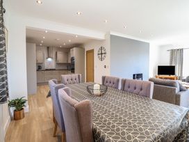 A dining room with a table and chairs adjacent to a kitchen at Tyn Y Weirglodd in Deiniolen