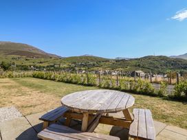 An outdoor seating area with a wooden table and benches at Tyn Y Weirglodd in Deiniolen