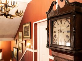 A hallway with a clock and paintings on the wall at Lonsdale House in Bowness-On-Windermere