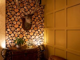 A snug with a deer head on a log wall with a plant and lighting at Lonsdale House Bowness-On-Windermere