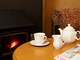A coffee cup and teapot on a table near a fireplace at Lonsdale House in Bowness-On-Windermere