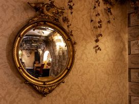 A mirror reflecting a hallway with a chair at Lonsdale House in Bowness-On-Windermere
