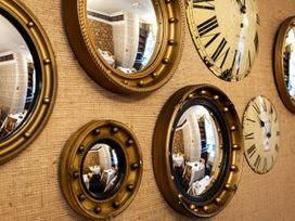 A wall with clocks and mirrors at Lonsdale House Bowness-On-Windermere