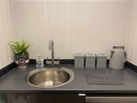 A kitchen countertop with a sink and containers for tea, sugar, and coffee at Lonsdale House in Bowness-On-Windermere