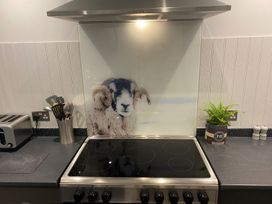 A kitchen featuring a stove and a splashback with a sheep design at Lonsdale House Bowness-On-Windermere