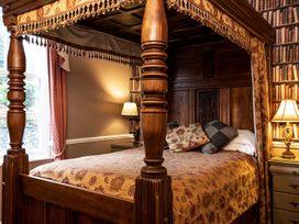 A bedroom with a canopy bed and bedside lamp at Lonsdale House in Bowness-On-Windermere