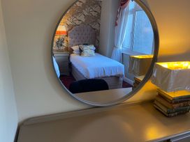 A bedroom with a mirror, bed, and lamp at Lonsdale House Bowness-On-Windermere