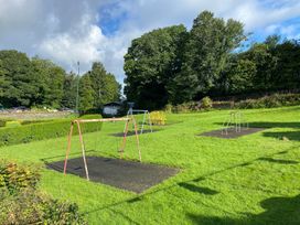 A playground featuring swings and a grassy area at Lonsdale House Bowness-On-Windermere