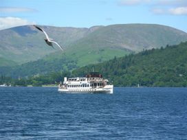 A boat on the water with mountains in the background at Lonsdale House in Bowness-On-Windermere
