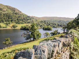 A lake surrounded by trees with a stone wall in Bowness-On-Windermere at Lonsdale House