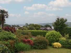 A garden view with various plants and houses at 7 Chycoose Parc