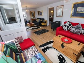 A living room with a red sofa and coffee table at Newgale Cottage in Haverfordwest